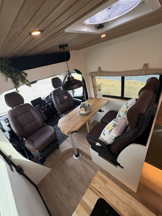 Bright front lounge with swivel seats and natural wood table
