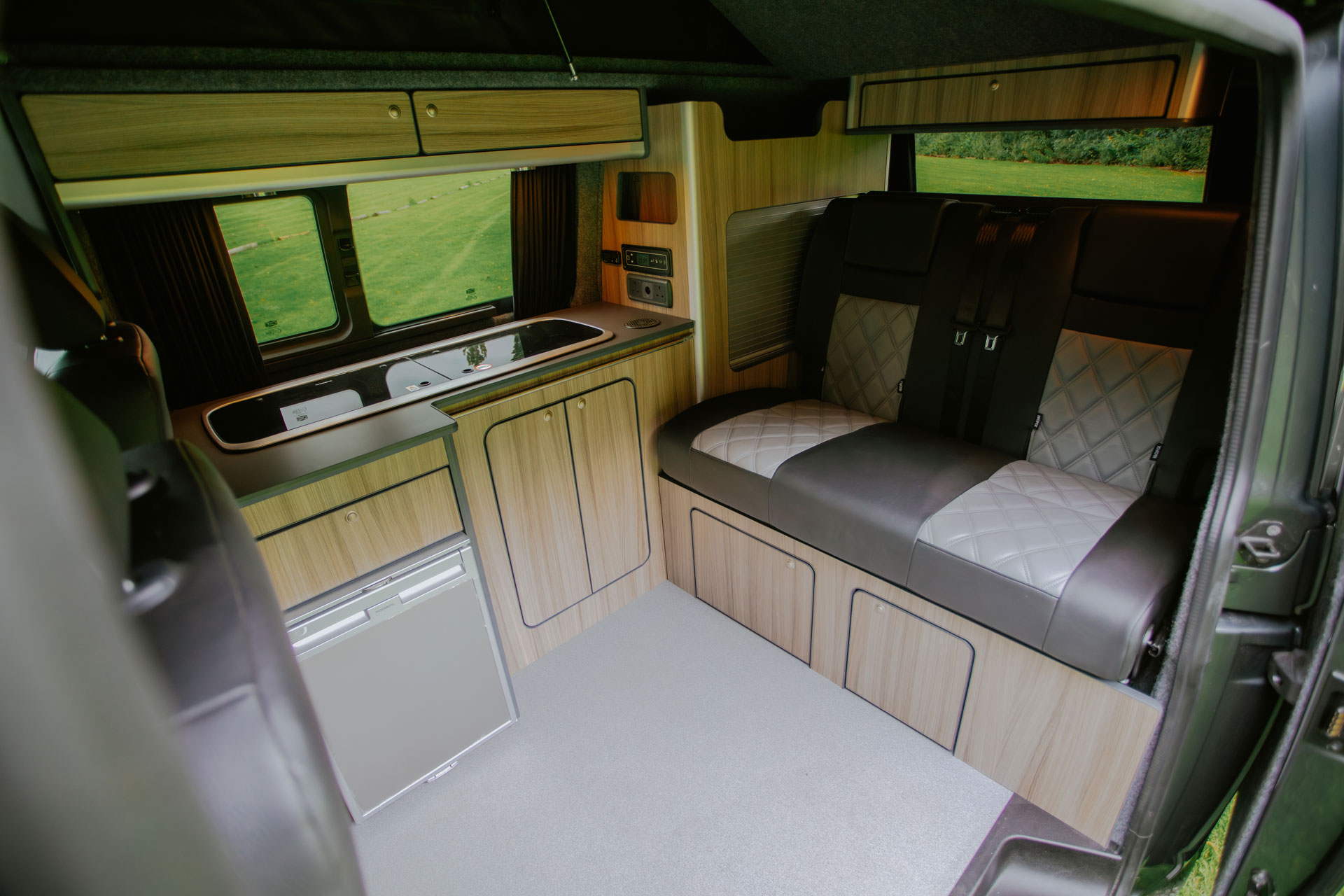 Campervan kitchen with tailored seating and pale wood cabinetry